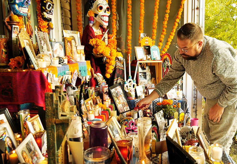 In front of his home in southwest Denver, Christopher Jorgenson lights candles at the ofrenda he constructed with his partner.